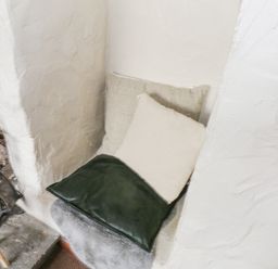 A small seating nook with cushions next to a fireplace with fire tools at Bofin in Oughterard County Galway