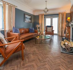 A living room with leather chairs wood log holder and a round coffee table at The Manor House Skerry Vore Bryn Pydew near Llandudno Junction
