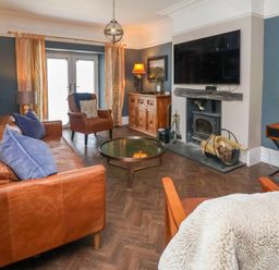 A living room with leather sofas a wood stove a television and a glass coffee table at The Manor House Skerry Vore Bryn Pydew near Llandudno Junction