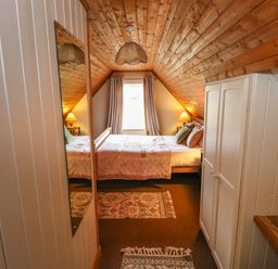 A bedroom with a wooden ceiling a bed two bedside tables with lamps and a window with curtains at Aggrafard in Oughterard County Galway