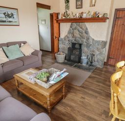 A living room with a stone fireplace a wooden coffee table two sofas and a wooden dining table with chairs at Corrib near Oughterard County Galway