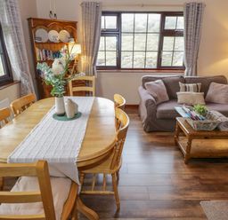 A dining area with wooden table and chairs next to a living room with sofa and coffee table at Corrib Near Oughterard County Galway