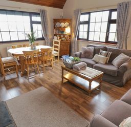 A living room with sofas a coffee table a dining table with chairs and a wooden cabinet at Corrib Near Oughterard County Galway