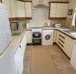 A kitchen with white appliances including refrigerator, washing machine, oven, kettle, toaster, and dishwasher near a window at Corrib Near Oughterard County Galway