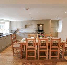 A kitchen with wooden dining table and chairs and built in cabinets at Tillers Cottage in Ebberston