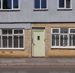 Exterior of a building with a light green door and white windows with shutters at 16 Church Street in Lyme Regis