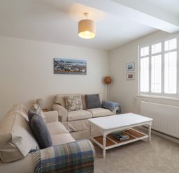 A living room with two sofas a coffee table a floor lamp and window shutters at 16 Church Street Lyme Regis