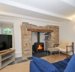 A living room with a television and wood stove at Sunrise Cottage in St Kew Highway near Wadebridge