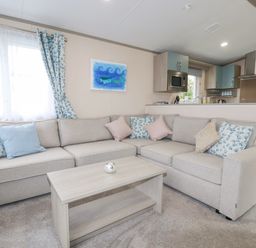A living room with a sectional sofa and coffee table next to a kitchen at The Mermaid A04 in Par