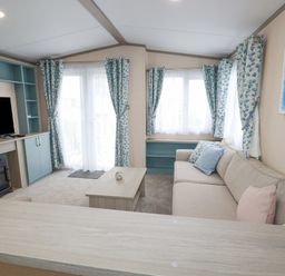 A living room with a sofa a coffee table a television and windows with curtains at The Mermaid A04 in Par