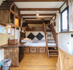 A small room with wooden bunk beds a wooden desk a mini fridge and two windows with curtains at Daisy Cow Shed 1 in Easton near Campsea Ashe