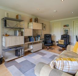 A living room with black armchairs a beige sofa with cushions shelves with books and decor at 50 Fernhill Heights in Charmouth