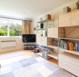 A living room with a sofa a television on a stand and shelving with books and cabinets at 50 Fernhill Heights in Charmouth