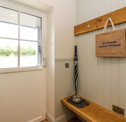 An entryway with a glass panel door a wooden bench an umbrella dog bowl and a hanging bag at Strawberry Cottage in Wester Essendy near Dunkeld