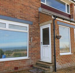 Front entrance of a brick house with white door and windows with reflections at 315 Filey Road Scarborough