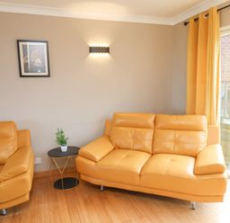A living room with two yellow leather sofas a small round table with a plant and yellow curtains at 315 Filey Road in Scarborough