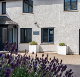 The exterior of a building with windows a door two planters and purple flowers in the foreground at Pen-y-Ghent in Kirkby Lonsdale