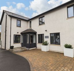 The exterior of a two-story building with a paved driveway and two white planters at Pen-y-Ghent in Kirkby Lonsdale