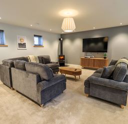 A living room with grey sofas a wooden coffee table a wall-mounted TV and a fireplace at Pen-y-Ghent in Kirkby Lonsdale
