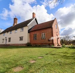 A two section house with brick and plaster walls surrounded by grass and trees at Brook Farm in St Nicholas near Halesworth