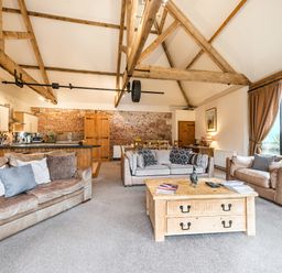 An open-plan living room with sofas a wooden coffee table a kitchen with appliances and a dining area at Mallard in Wheatacre