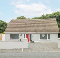 A single story house with a red front door and gravel driveway at Wychwood in Hook near Haverfordwest