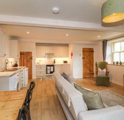 An open plan living room and kitchen with wooden doors and flooring at 8 Rookhaye in Salisbury