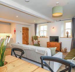 A living room with sofas a wooden cabinet a dining table with chairs and a kitchen area at 8 Rookhaye in Salisbury