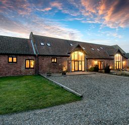 A brick house with large windows and a gravel driveway and lawn at Teal in Wheatacre