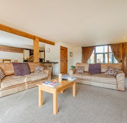 A living room with two sofas, cushions, a wooden coffee table, and a window with curtains at Teal in Wheatacre
