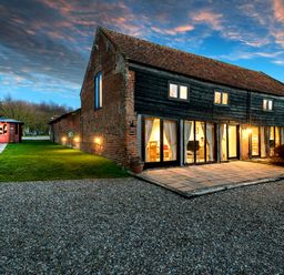 A barn style house with large windows and a small wooden gazebo on a lawn at Snipe in Wheatacre