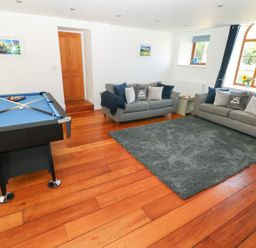 A room with two grey sofas around a grey rug and a blue pool table on a wooden floor at Dalton Cottage in Llansaint