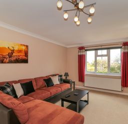 A living room with a sectional sofa and cushions a coffee table and a wall-mounted television at Te Papa in North Petherton