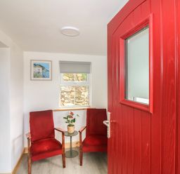 A small seating area with two red chairs and a table with a plant at Curragh Cottage in Rathimney near New Ross County Wexford