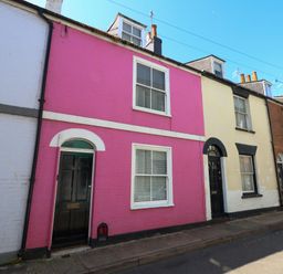 A row of brick terraced houses with colorful facades and black doors on a street at Georgian Hideaway in Weymouth
