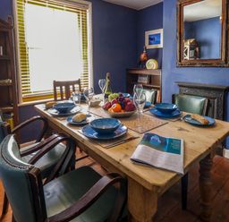 A dining room with a wooden table set for six with blue plates bowls and glasses at Georgian Hideaway in Weymouth