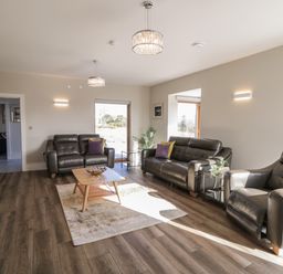 A living room with leather sofas a coffee table and large windows at Moorhen House in Loughanure near Annagry County Donegal
