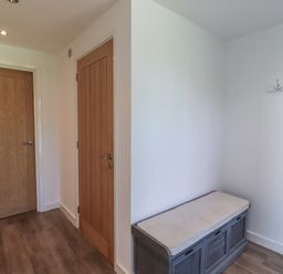 A small room with two wooden doors a cushioned bench and a coat rack at Otters Cove in Belford