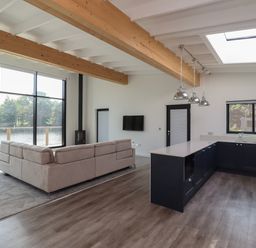 A living room with a sectional sofa and a kitchen with pendant lights and a skylight at Otters Cove in Belford