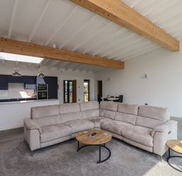 A living room with a beige sectional sofa and round wooden tables with metal legs at Otters Cove in Belford