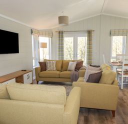 A living room with beige sofas a wall-mounted television and a dining table with chairs at 23 Meadow Retreat in Dobwalls