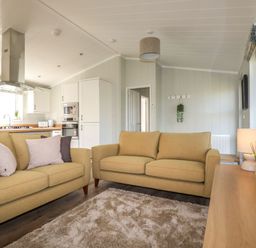 A living room with two sofas a rug a wooden table a lamp and an open kitchen at 23 Meadow Retreat in Dobwalls