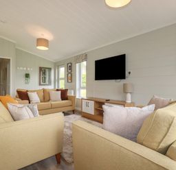 A living room with three beige sofas a wall mounted TV and a wooden TV stand at 6 Faraway Fields in Dobwalls