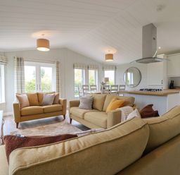 An open living and kitchen area with sofas dining table and kitchen island at 6 Faraway Fields in Dobwalls