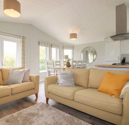 A living room with two sofas pillows a dining table and chairs a kitchen area with a stove and vent hood at 6 Faraway Fields Dobwalls