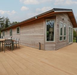 A wooden house with a large deck and outdoor dining table and chairs at 6 Faraway Fields in Dobwalls
