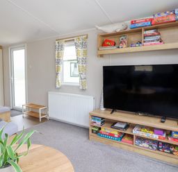 A living room with a flat screen television board and board games at Windermere Lodge in Morecambe