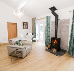 A living room with a fireplace and dining area at The Barn in Astwood Bank