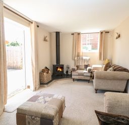 A living room with armchairs a wood burner and curtains at The Old Chapel in Foxley near Bawdeswell