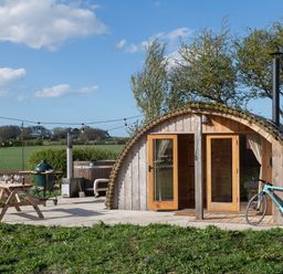 An outdoor glamping pod with a picnic table grill hot tub and bicycle at Glamping Pod 1 Comfort in Lebberston